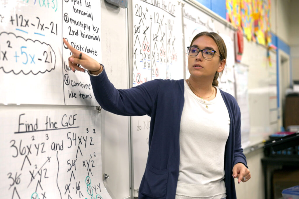 Woman pointing at whiteboard with math problems