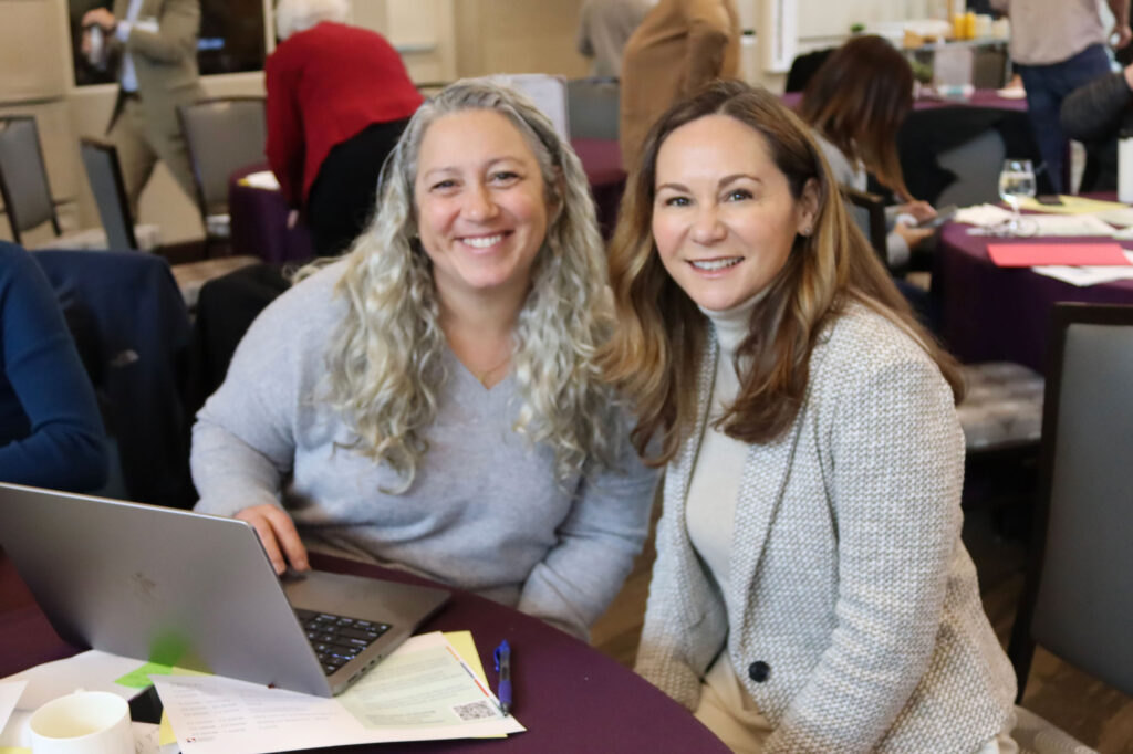 Two adults smiling behind laptop