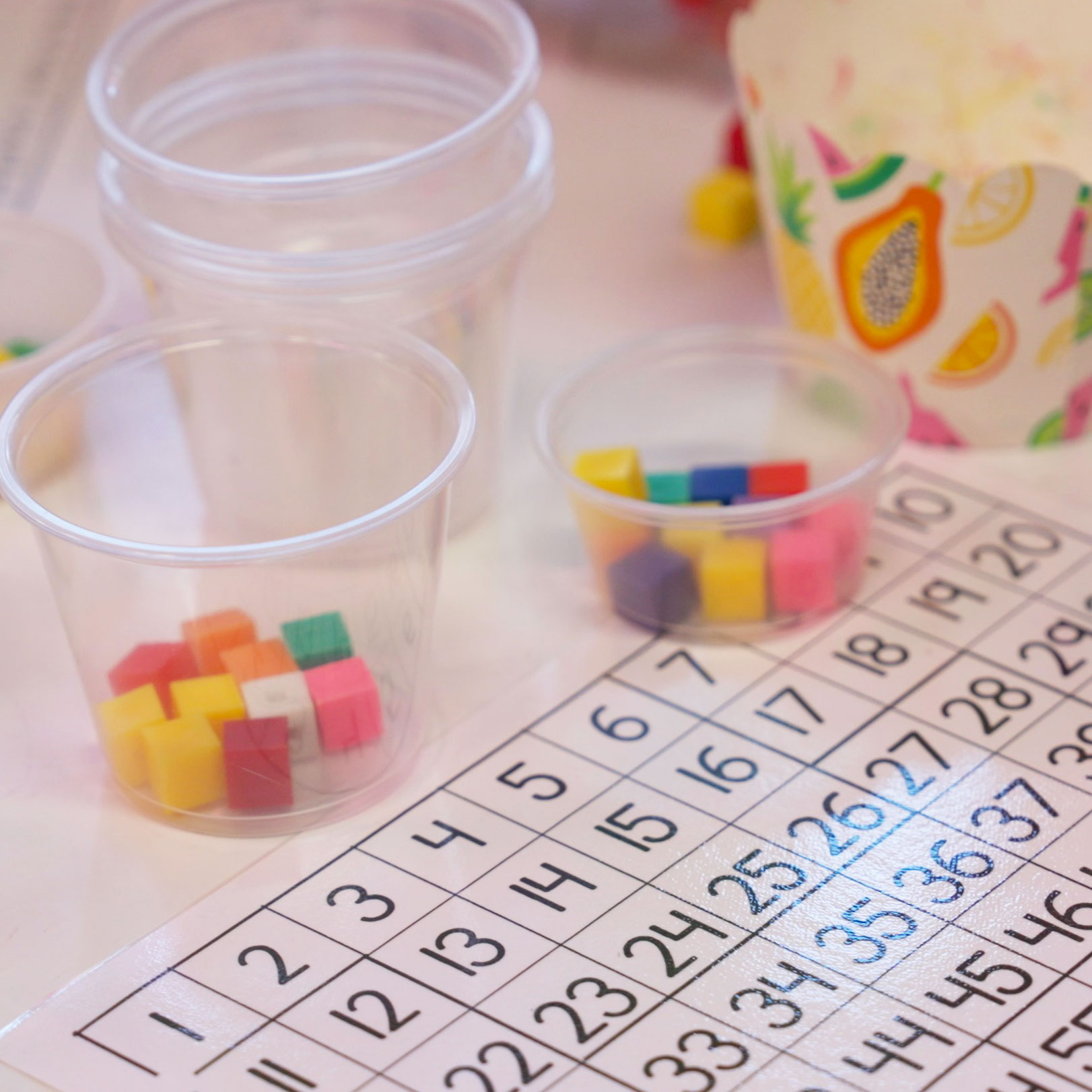 Number chart with plastic cups filled with colored blocks